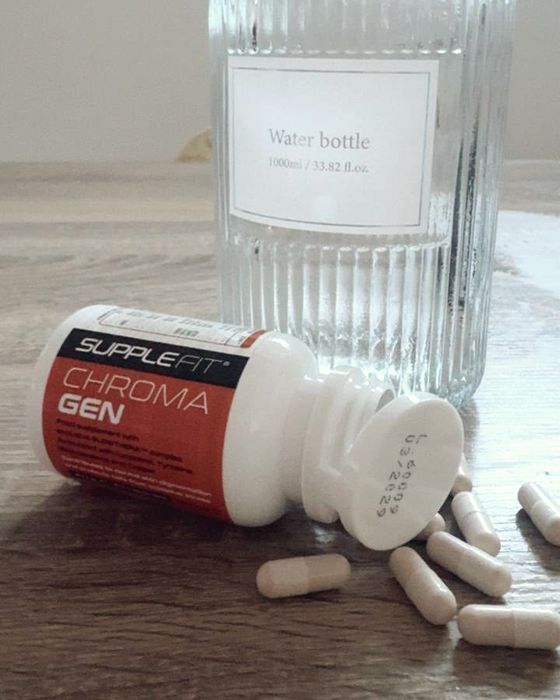 Un flacon de compléments alimentaires et des gélules à côté d'une carafe d'eau